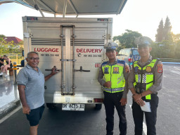 Satlantas Polres Bandara Ngurah Rai Bagikan Stiker Layanan Polisi 110 kepada Masyarakat Pengguna Jasa Bandara