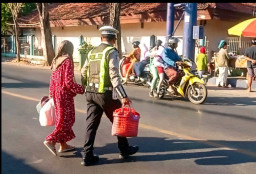 Aksi Humanis Anggota Satlantas Polres Sampang Seberangkan Ibu Bawa Barang Banyak di depan Pasar Srimangun