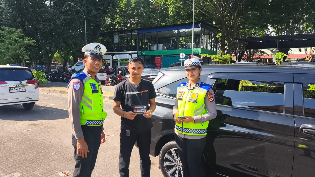 Satlantas Polres Bandara Ngurah Rai Bagikan Stiker Keselamatan Berkendara kepada Pengguna Jasa Bandara